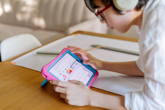 Pre-teen Boy wearing headphones designing a project and using a tablet