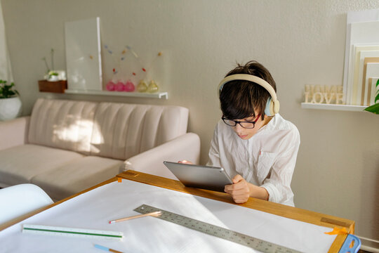 Pre-teen Boy wearing headphones designing a project and using a tablet