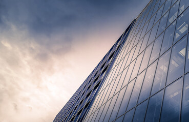Fototapeta na wymiar Business glass building with lots of reflecting windows and the gloomy sky