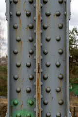 Metal construction poles with metal rivets are painted gray through which rust penetrates and the...
