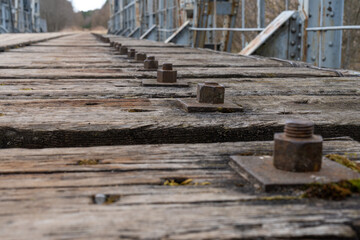 Low angle of view on metal bridges and wooden sleeper mount bracket heads with nuts.