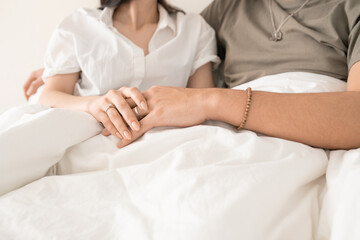 Fototapeta na wymiar Hands of young amorous married couple sitting in bed