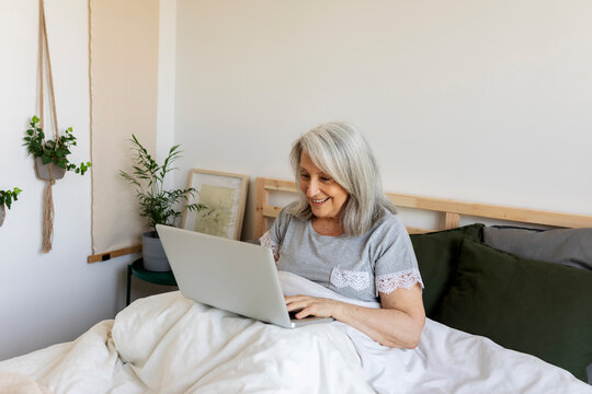 relax mature woman with laptop on bed
