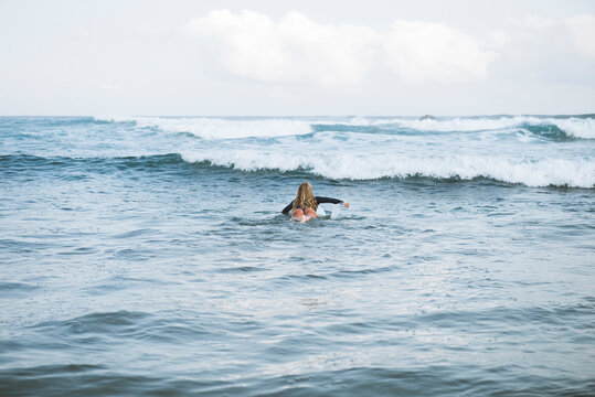 Female surfer swimming towards wave