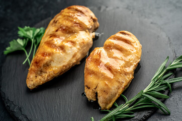 two grilled chicken breasts on a stone background