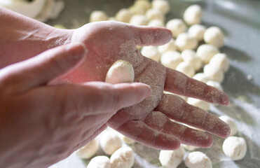 The process of making homemade dumplings. Kneading the dough. Women's hands. Dumplings, pielmieni,...