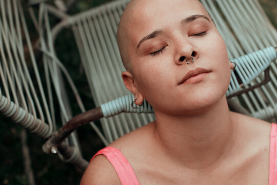 Emotional portrait of a beautiful bald woman lying in a garden