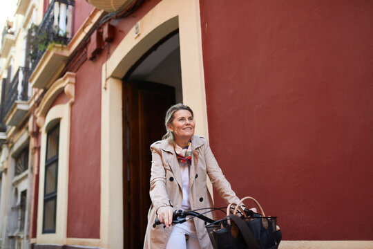 Senior Woman Biking Through City