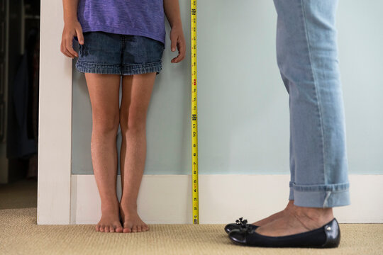 Barefoot Young Girl Measuring her height with just legs showing 