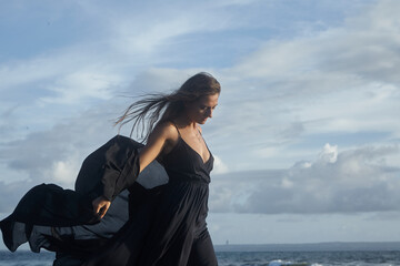 Girl on the background of the ocean catches the wind
