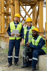 Three intercultural builders in uniform on construction site