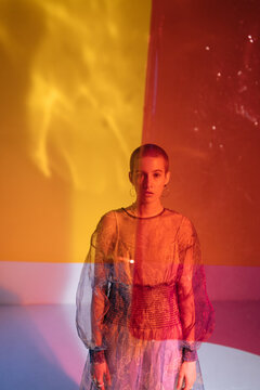 Fashionable bald woman in translucent dress in studio