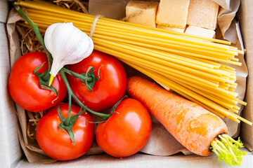 ingredients for italian cuisine dishes in delivery box - pasta, tomatoes, carrot, garlic, cheese parmesan