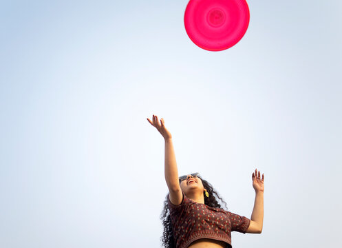Young Indian woman playing with flying disc at outdoors
