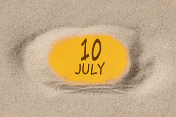 July 10. 10th day of the month, calendar date. Hole in sand. Yellow background is visible through hole. Summer month, day of the year concept