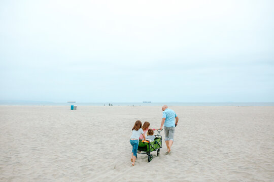 Dad pulling green wagon on beach