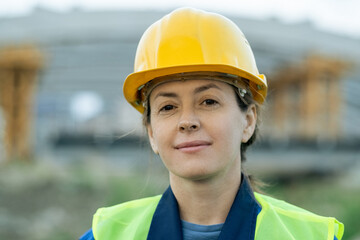 Successful female builder in protective helmet looking at you