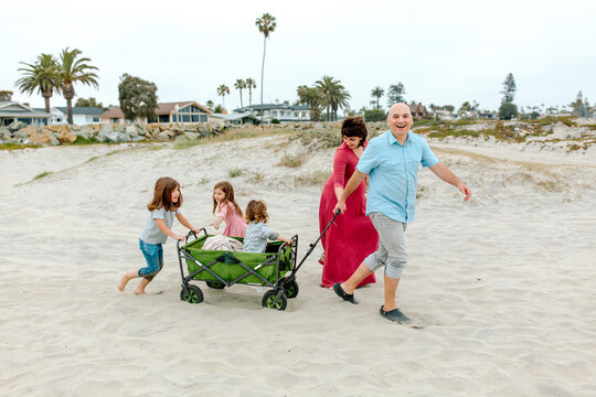 Parents pulling green wagon across sand