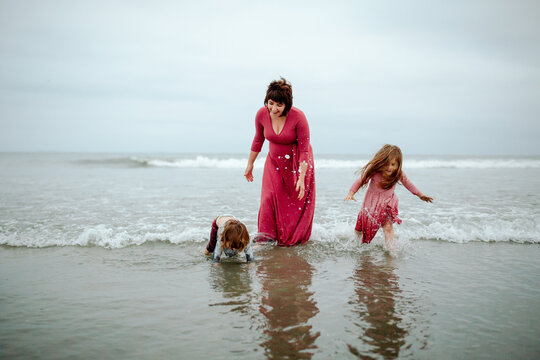 Expectant mom wading in ocean with children
