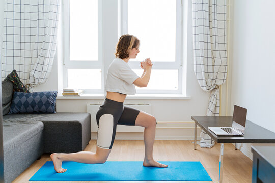 Young woman doing fitness exercise near laptop at home