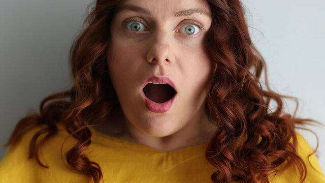 Happy carefree surprised woman palms looks with amazement at camera smiles, afraid and surprised of shock with open mouth