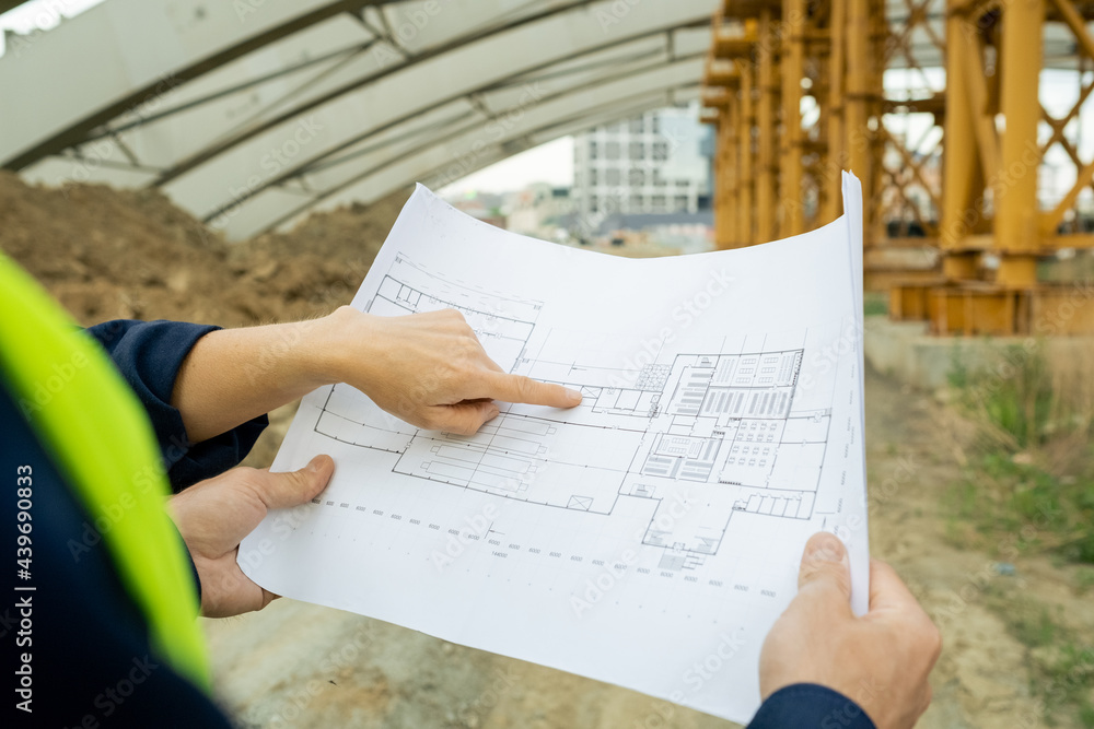 Poster Hand of female engineer pointing at sketch of unfinished construction during discussion