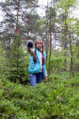 Naklejka na ściany i meble girl holds in her hand a glass jar with freshly picked ripe blueberries against the background of the forest. Natural antioxidant, delicious and healthy food