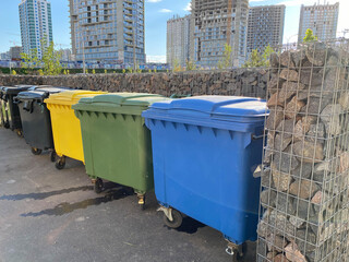 Black, yellow, green and blue plastic large modern containers for separate collection and subsequent ecological recycling of waste in a new area of the city