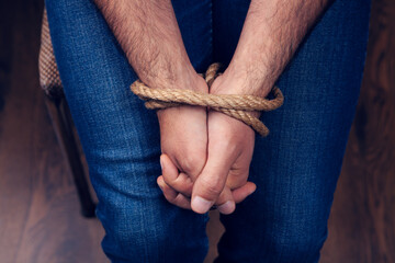 the man's hands are tied with a rope