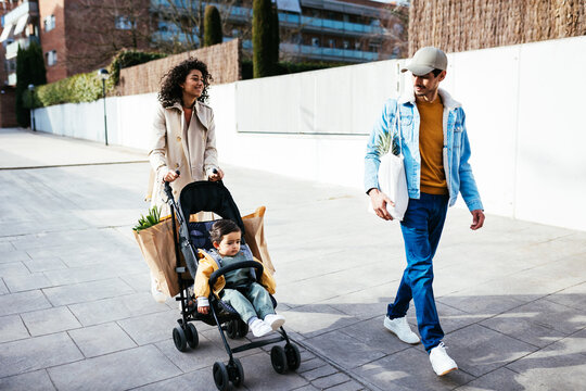 Young Indian parents with baby walking on street after weekend shopping