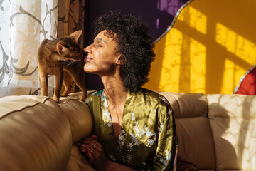 Black woman communicating with cat on sofa
