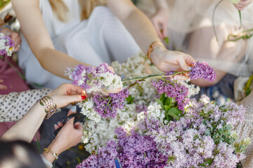 Girls weave wreaths on their heads from fresh flowers of lilac and wildflowers