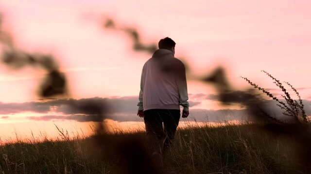 Young lonely guy walks at sunset. Evening time of day