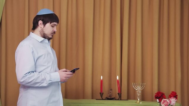 Before the chuppah ceremony, a Jewish groom in the synagogue hall dials an SMS by phone