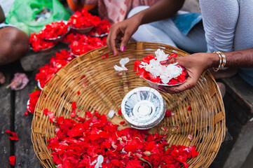 Young woman preparing red flower petals for  a spiritual ritual of Ganga Aarti