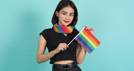 LGBTQ girl and pride flag. Sexy Lesbian girl and LGBTQ flag standing. blue green background. Asian LGBTQ woman with rainbow scarf on neck. Energetic cheerful. LGBTQ concept. LGBTQA+ Pride Month.