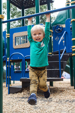 Little boy  hanging down the monkey bar in the park