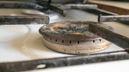 Dirty gas stove in the kitchen for cooking with vegetable oil stains and burnt food debris on the surface, close-up. Selective focus. Grease-covered gas hob in the kitchen.
