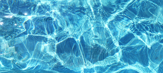 Fototapeta na wymiar Blue rippled water surface of turquoise swimming pool. Summer vacations resort concept. Background of water ripple under bright sunny sky. Full frame texture. Banner with place for text.