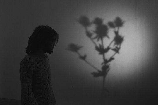 A silhouette of a man with a shadow of a flower in the background.