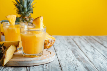 Tasty pineapple juice in glass with ingredients on white wooden table with yellow summer background. Fresh natural pineapple juice cocktail and juice Glass with copy space