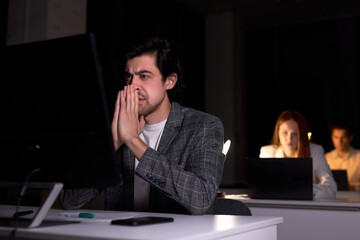 Portrait of exhausted serious caucasian male worried by work on computer in office at night, miss the deadline, has a lot of troubles, in dark room, sit thinking. work, business concept
