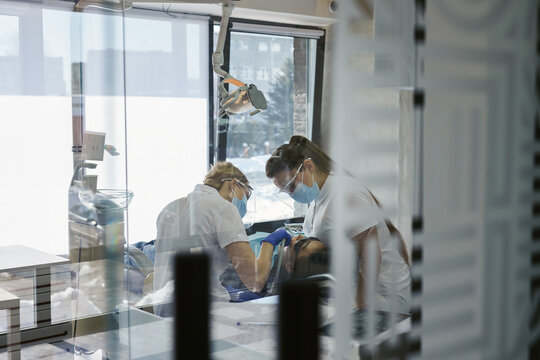 Female assistant helping doctor doing surgery of oral cavity 