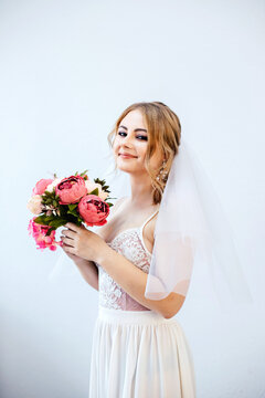 Brunette girl in a wedding dress. Bride in a white dress with a bouquet in her hands. Makeup.