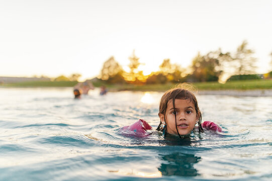 Girl swimming in pond at sunset. 