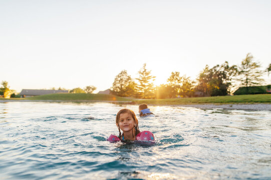 Kids happily swimming in pond at sunset. 