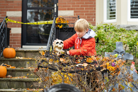 Boy Setting up Skull Scary Halloween Decorations in Front Yard for Trick or Treat