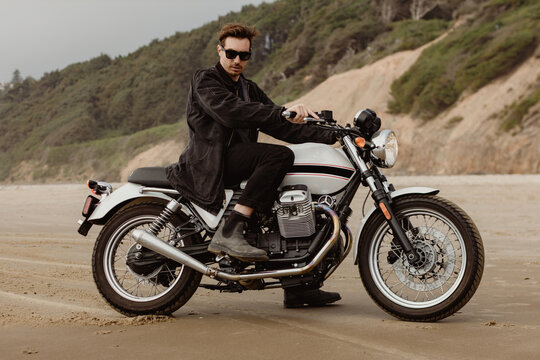 Trendy man riding Motorcycle on Beach