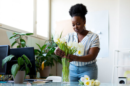 Woman Putting Flowers In Vase