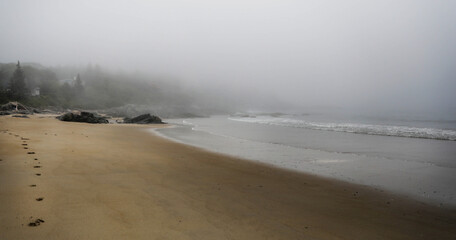 Footprints on the beach on a misty day in Maine.